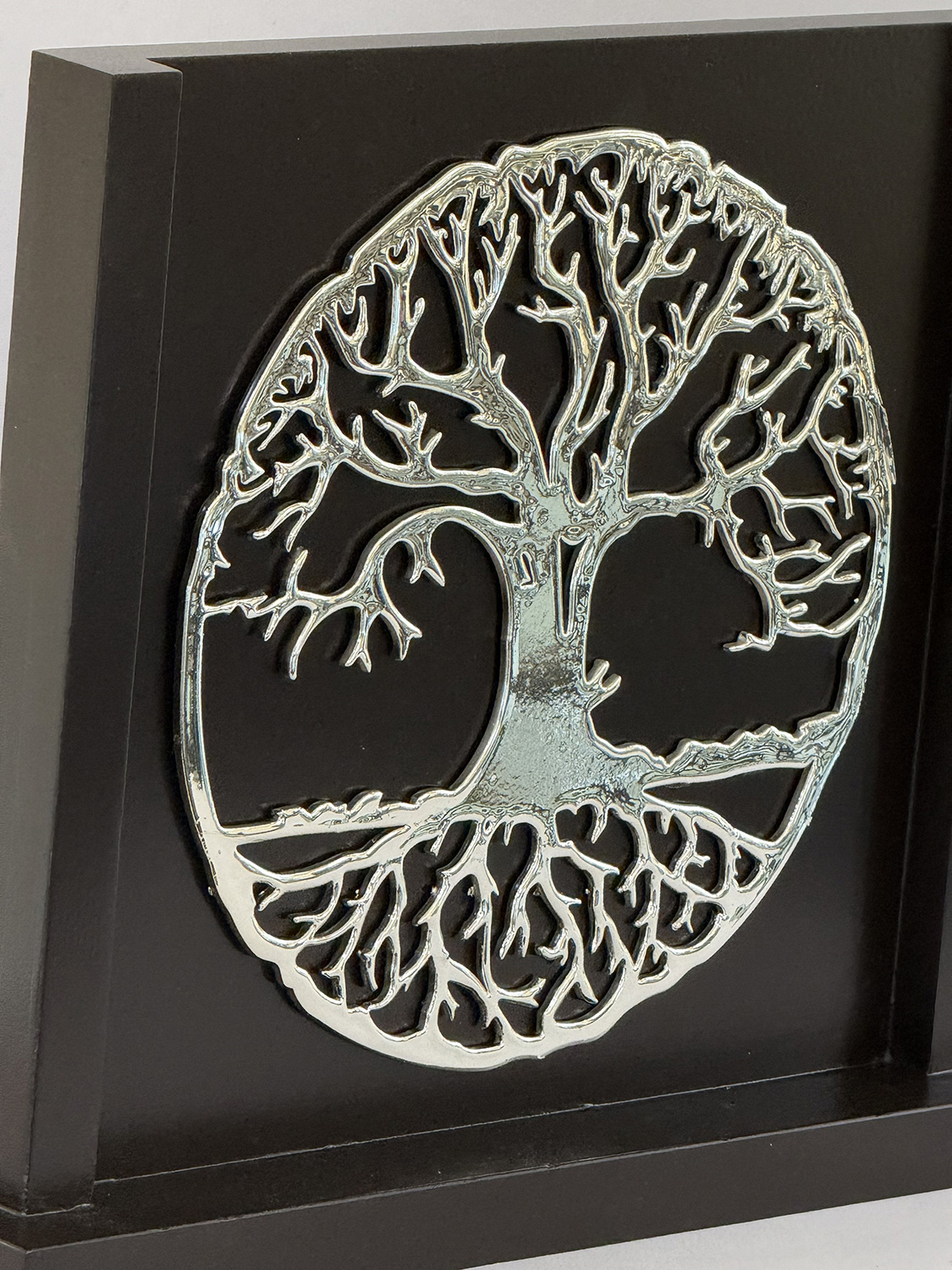 Circular metal Tree of Life silhouette mounted on a black display plaque, framed as wall art
