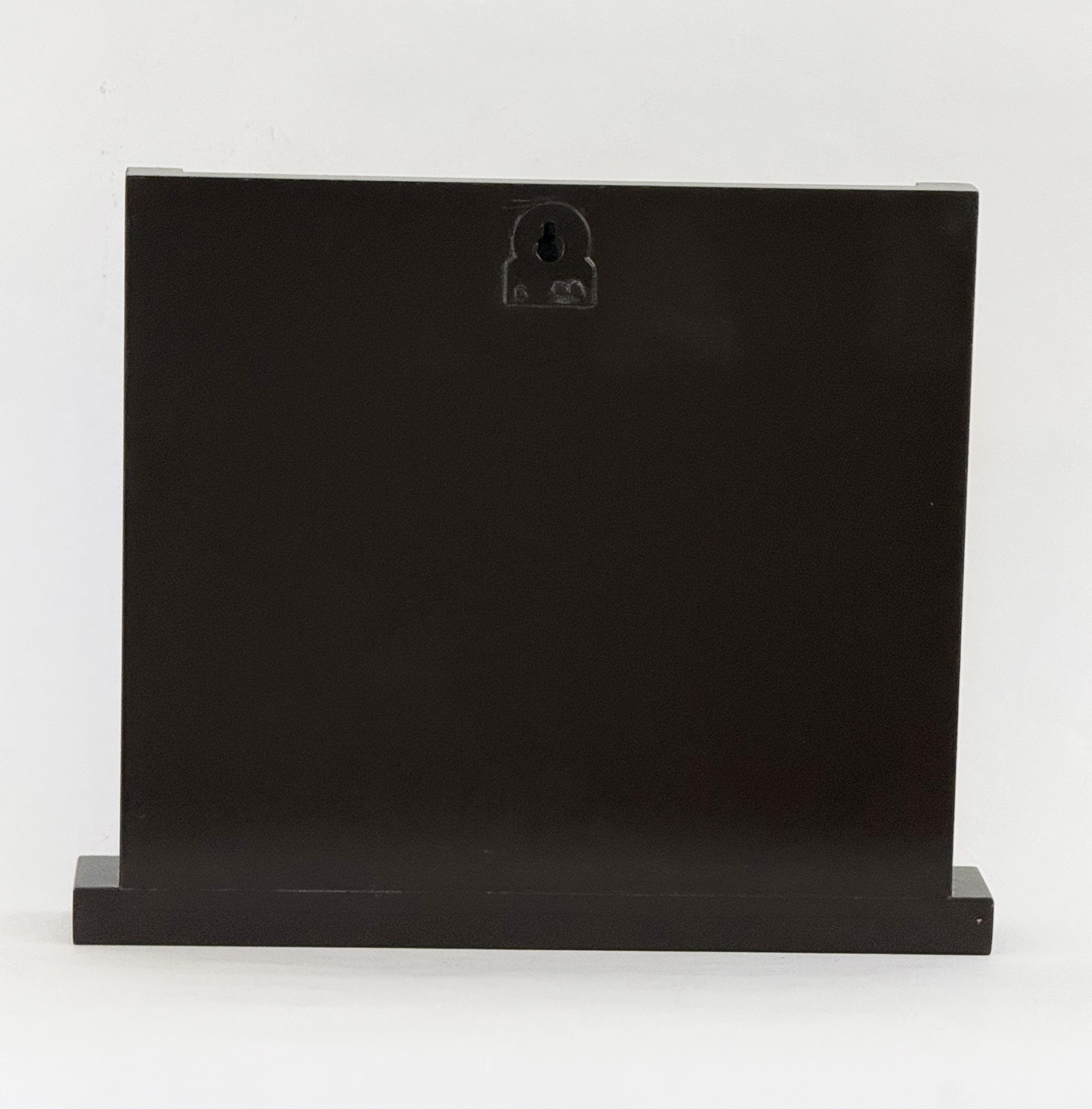 Black rectangular display cabinet on a low pedestal with a small keyhole plate near the top center of its front face