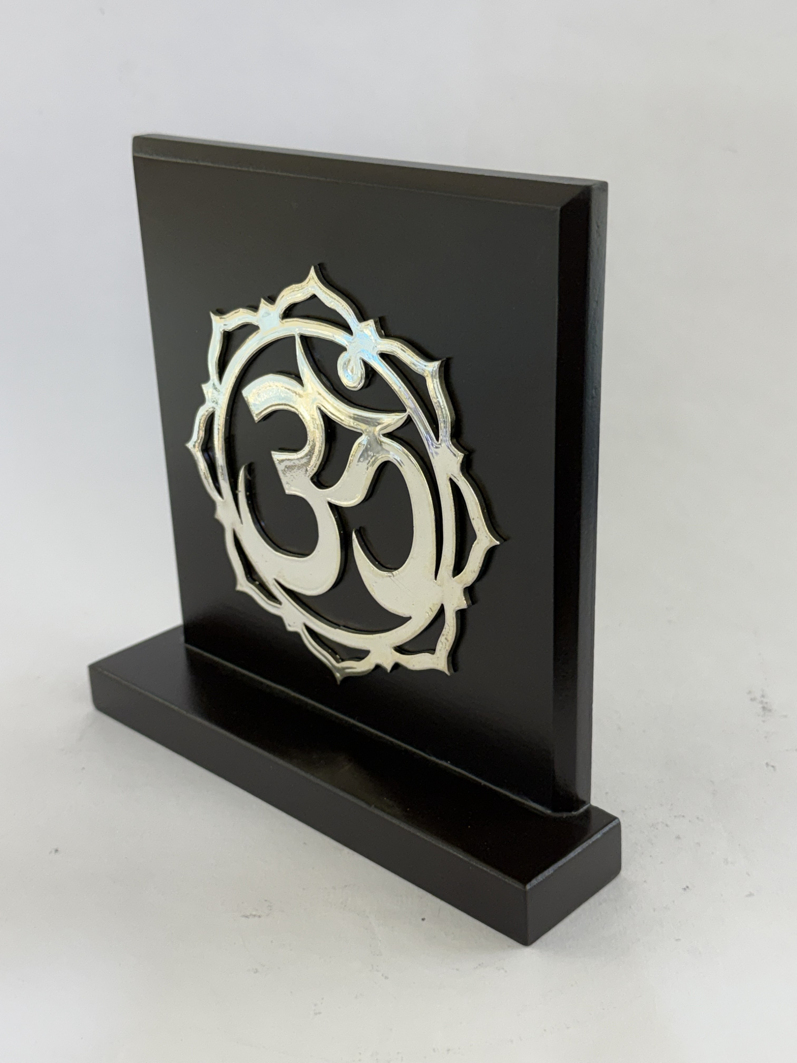 Black rectangular display panel on a weighted base with an intricate silver decorative emblem attached to the front panel in a cutout design.