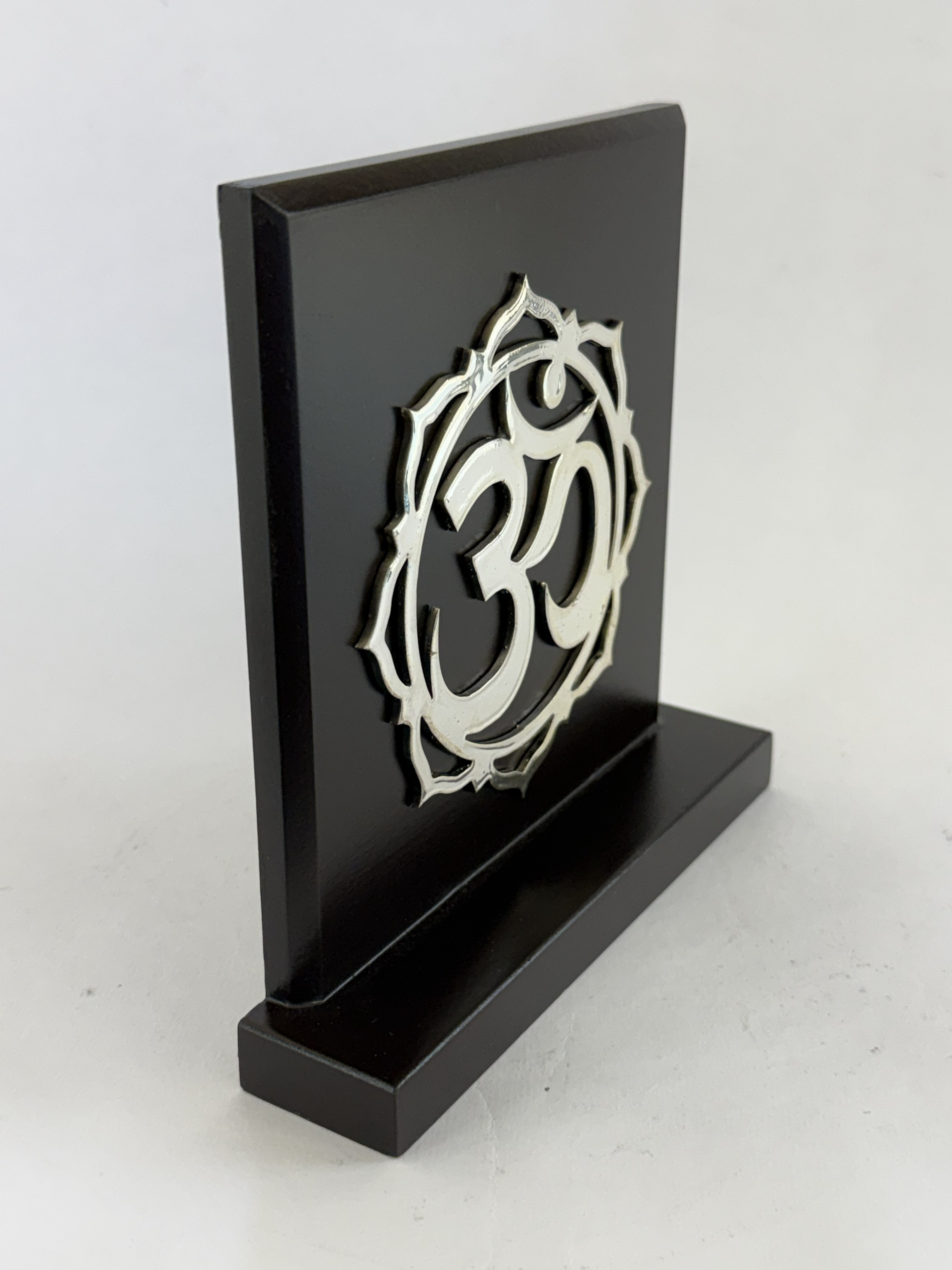 Black rectangular plaque on a stand with an intricate silver circular monogram emblem attached.