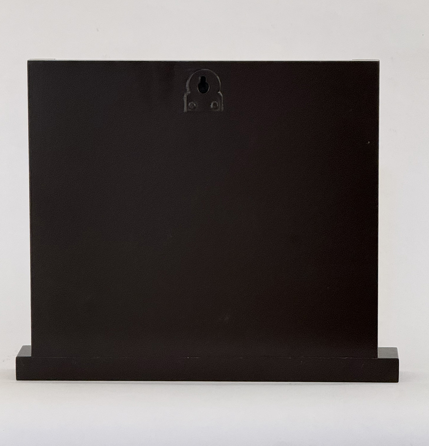 Black rectangular display block on a low base, photographed against a white background. A small, decorative keyhole-shaped detail sits near the top center of the box.
