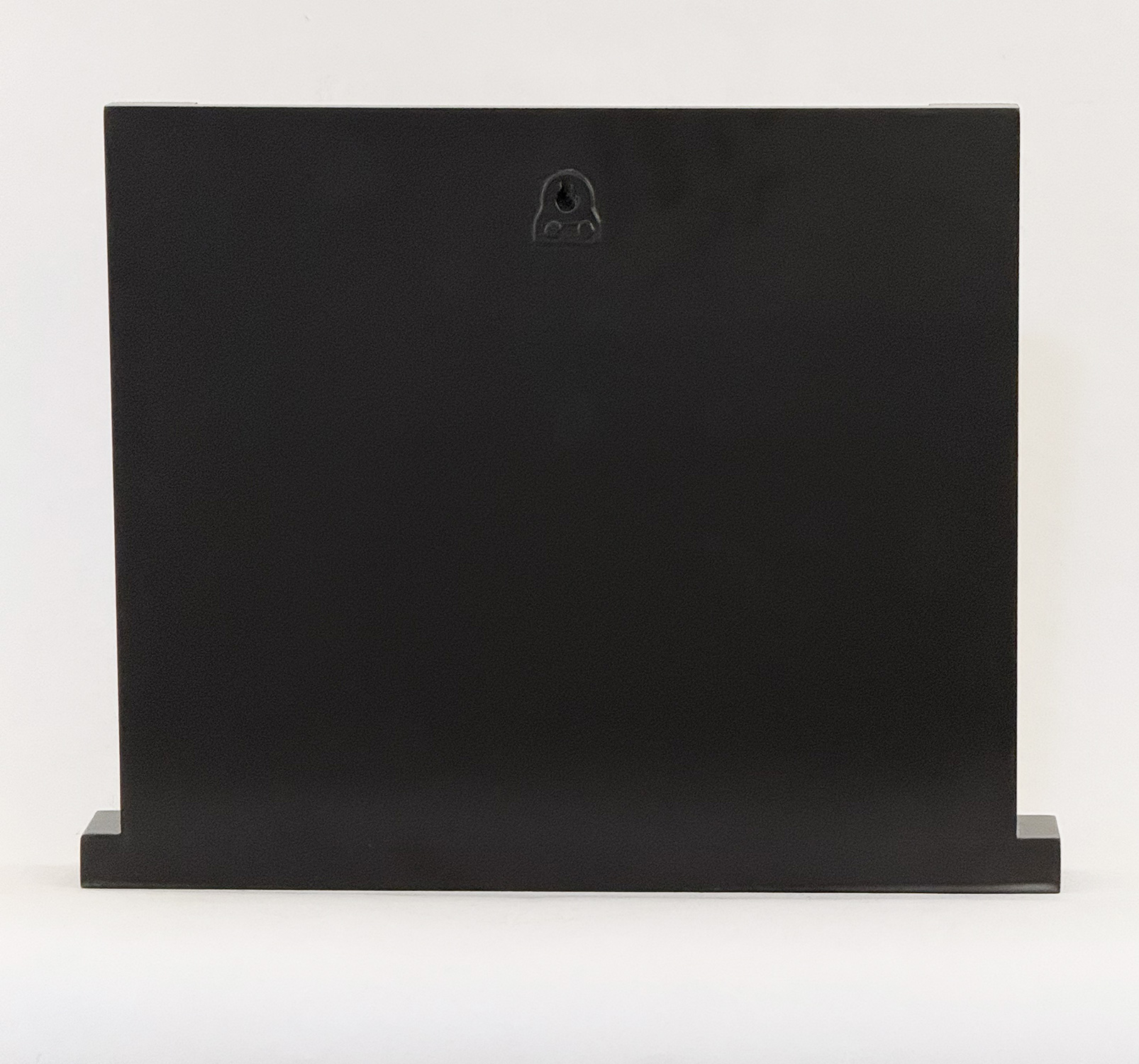 Back view of a tall black rectangular cabinet with a small circular keyhole near its top center, on a low base against a white background.