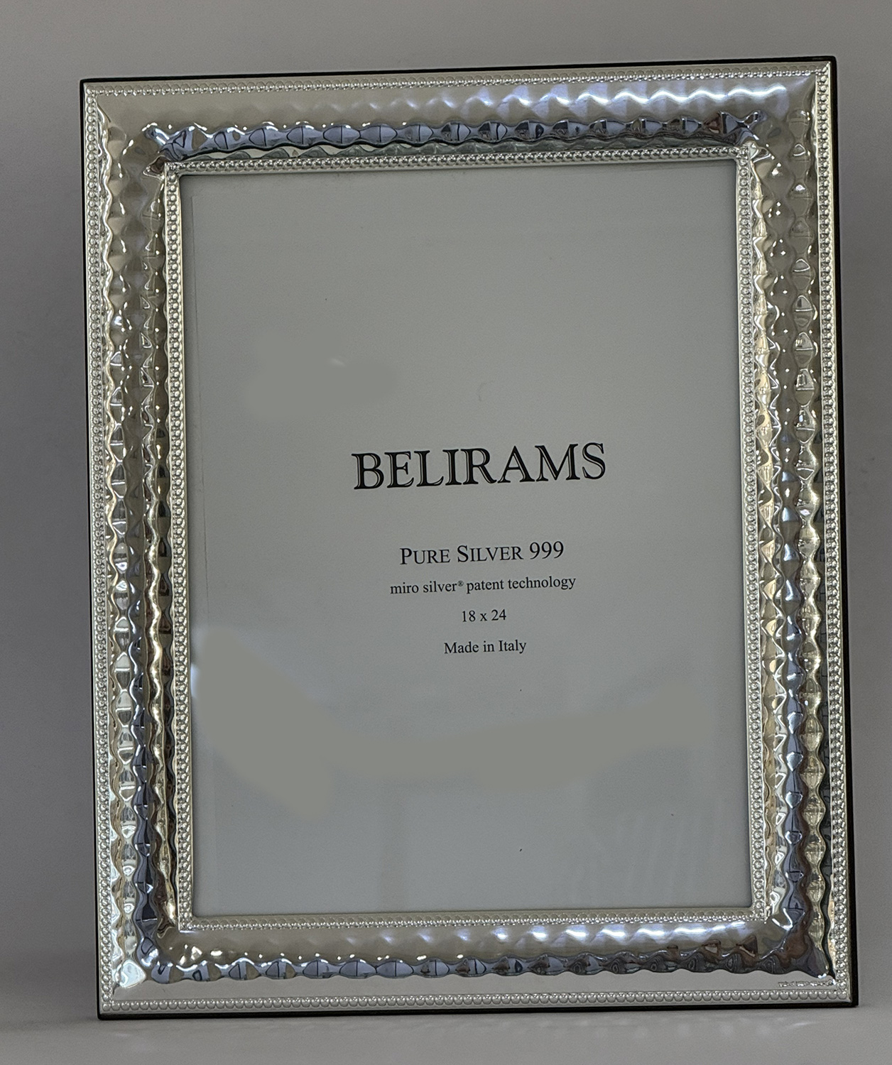 Shiny silver decorative picture frame with a beaded inner edge and a card inside reading BELIRAMS, Pure Silver 999, Made in Italy.