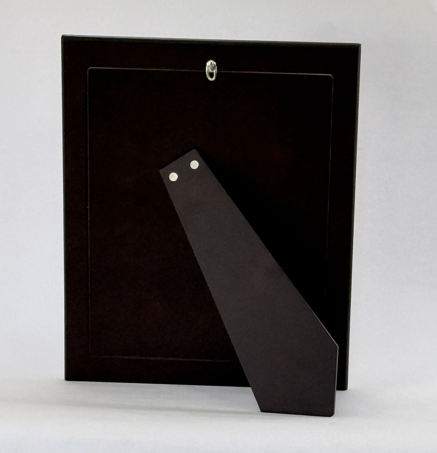Tall black rectangular box with a diagonal black strap attached to its front, riveted near the strap's top end.