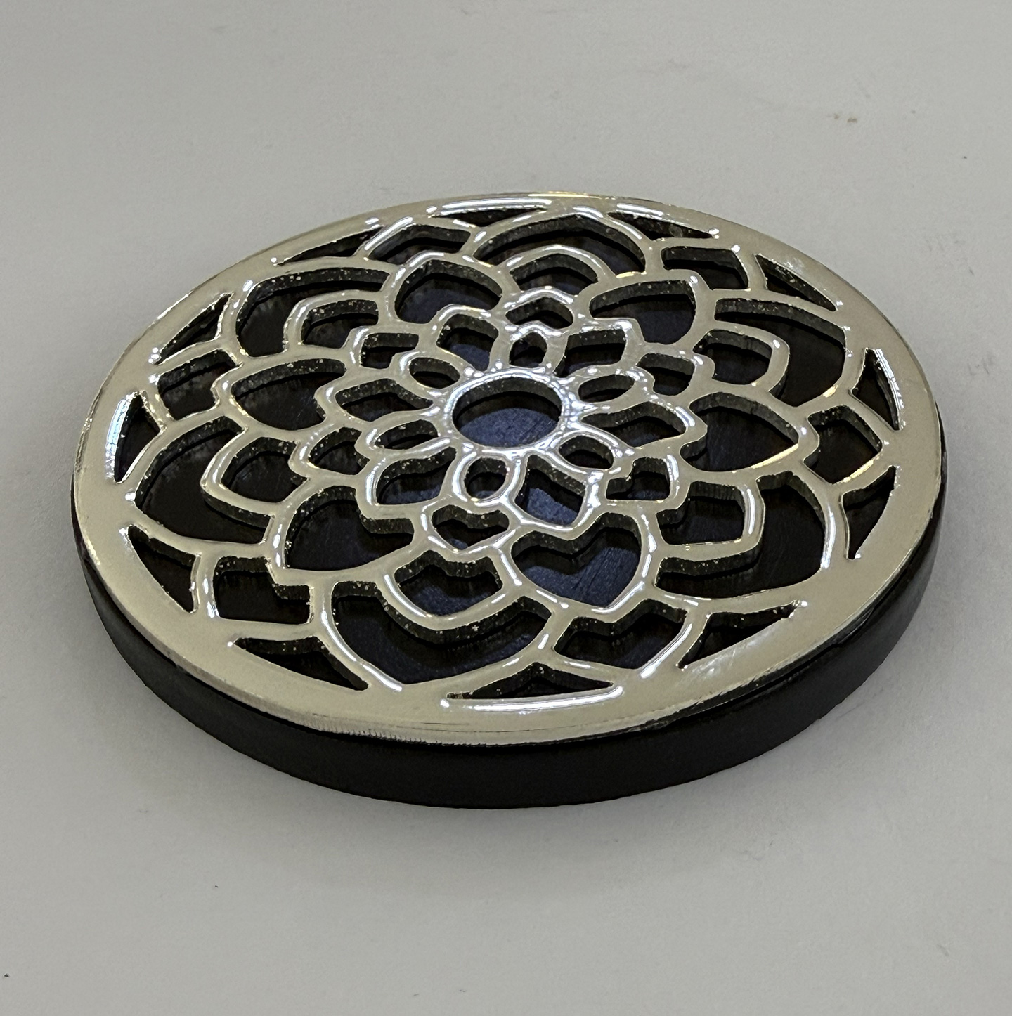Round metal drain grate with an intricate floral lattice pattern on a circular base.