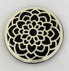 Round decorative metal plate with a layered white floral rosette cutout pattern against a black background, wall decor.