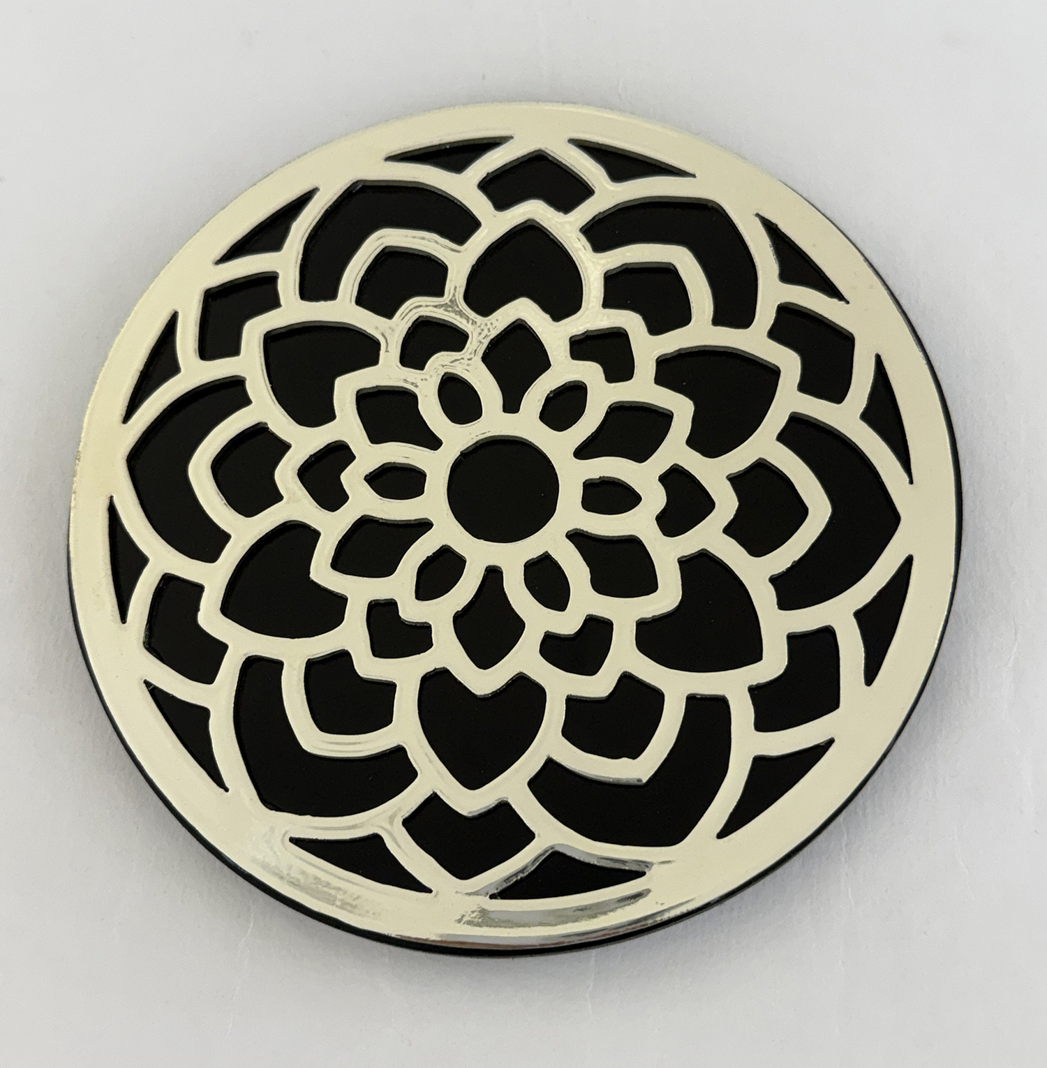 Round decorative metal plate with a layered white floral rosette cutout pattern against a black background, wall decor.