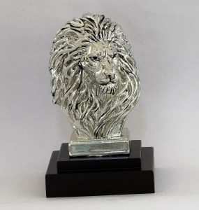 Silver lion head sculpture on a dark wooden pedestal.