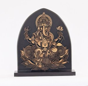 Wooden laser-cut panel depicting the Hindu deity Ganesha with multiple arms, seated on a lotus, in an arched, black background art piece on a pedestal