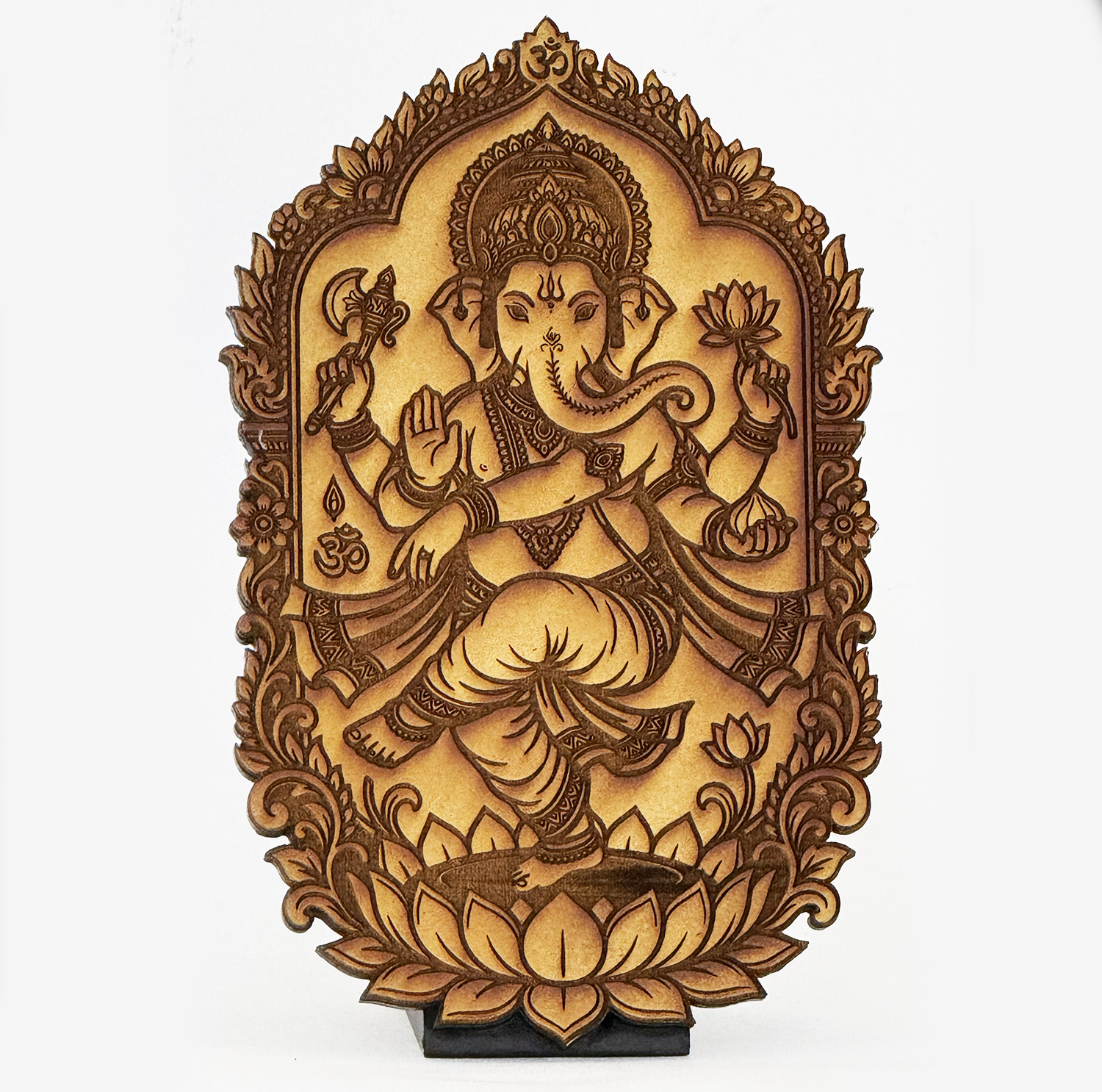 Intricately carved wooden panel depicting the Hindu god Ganesha seated on a lotus, with multiple arms holding a lotus and an axe, framed by floral borders.