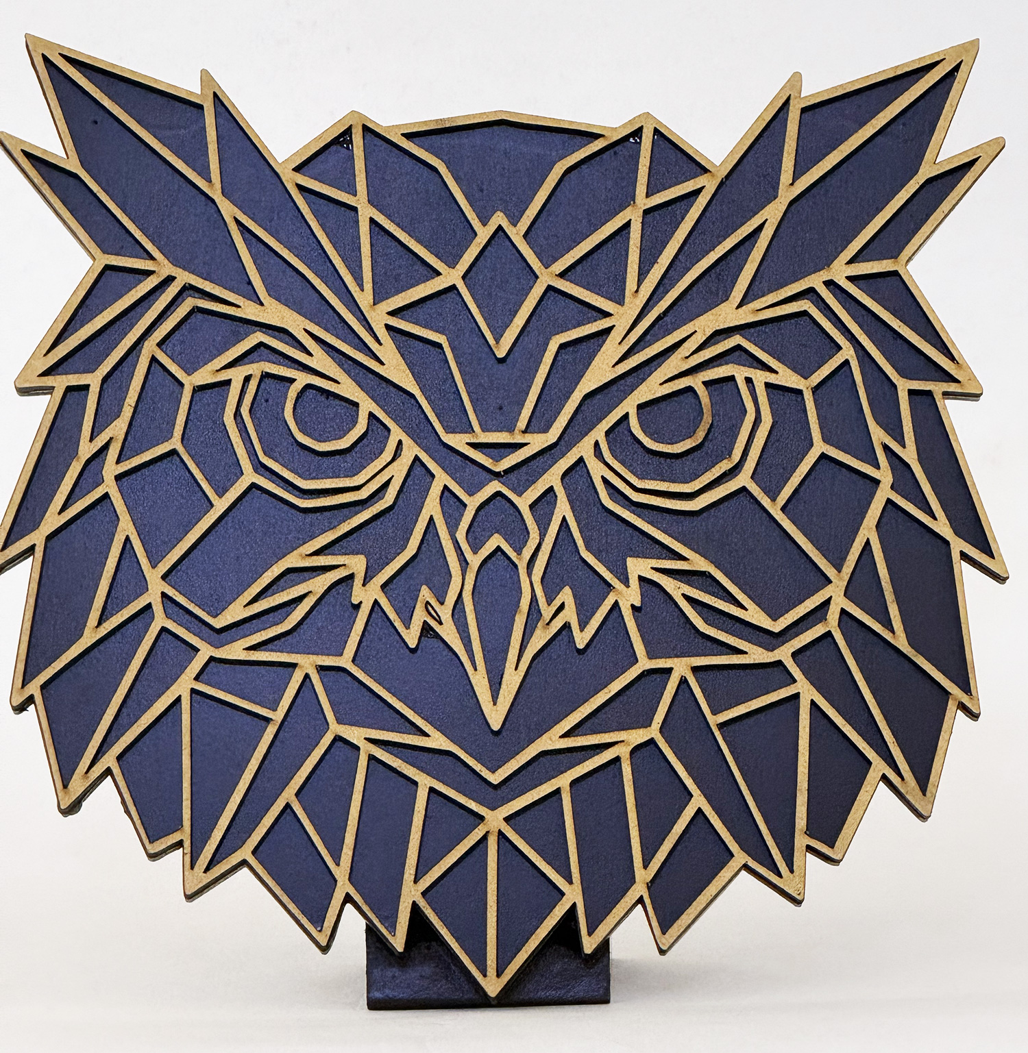 Geometric owl sculpture in blue panels with gold edges on a dark pedestal.