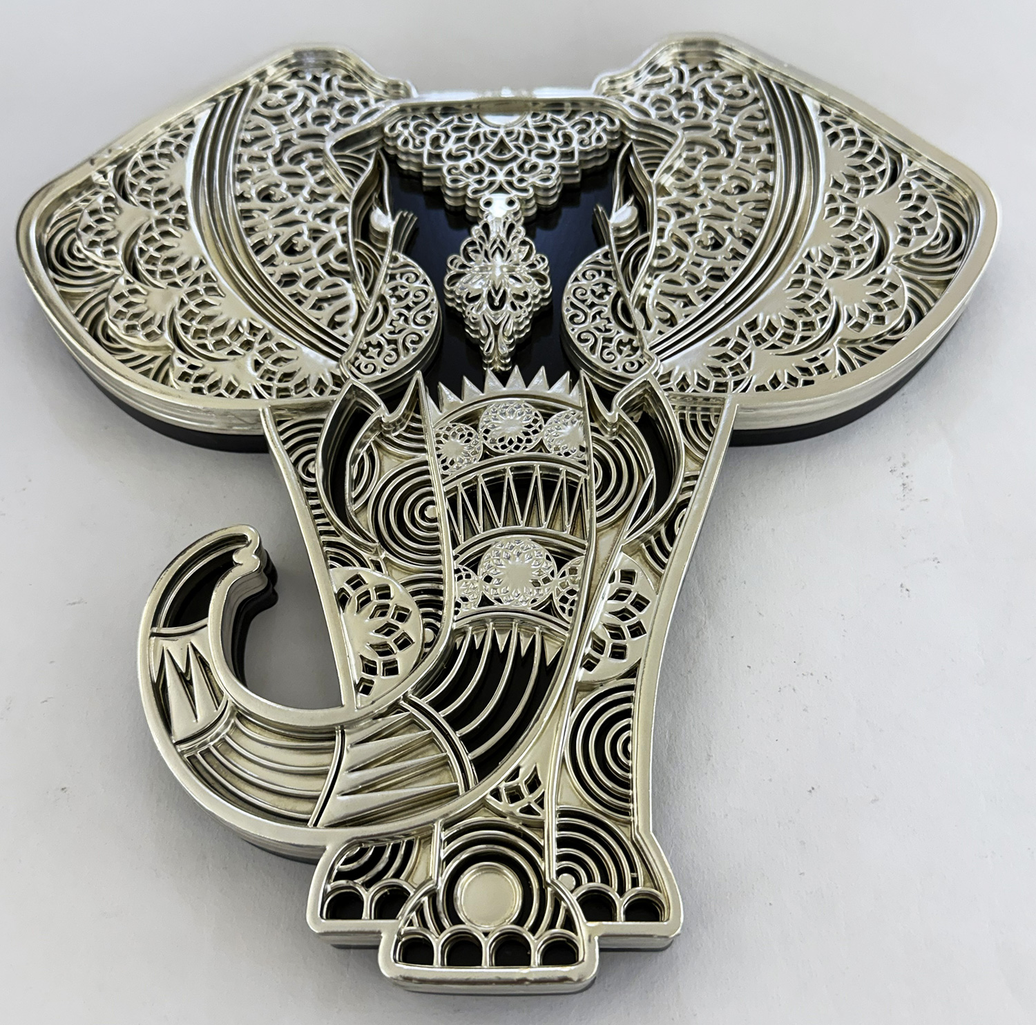 Intricate metal filigree crucifix with ornamental lacework and a dark background scene behind the cross center”,